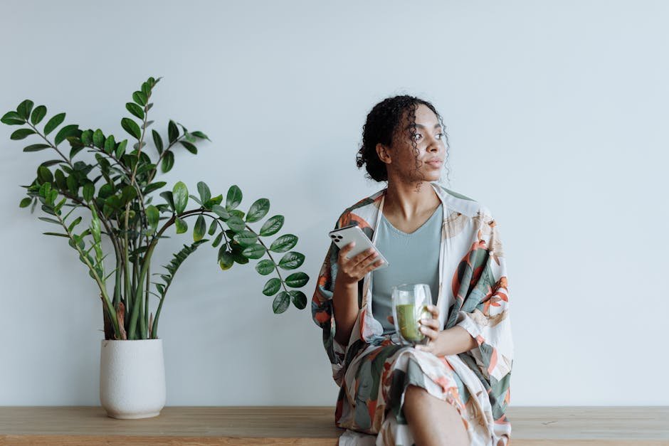 A thoughtful woman enjoying tranquil indoor space with a plant and drink.